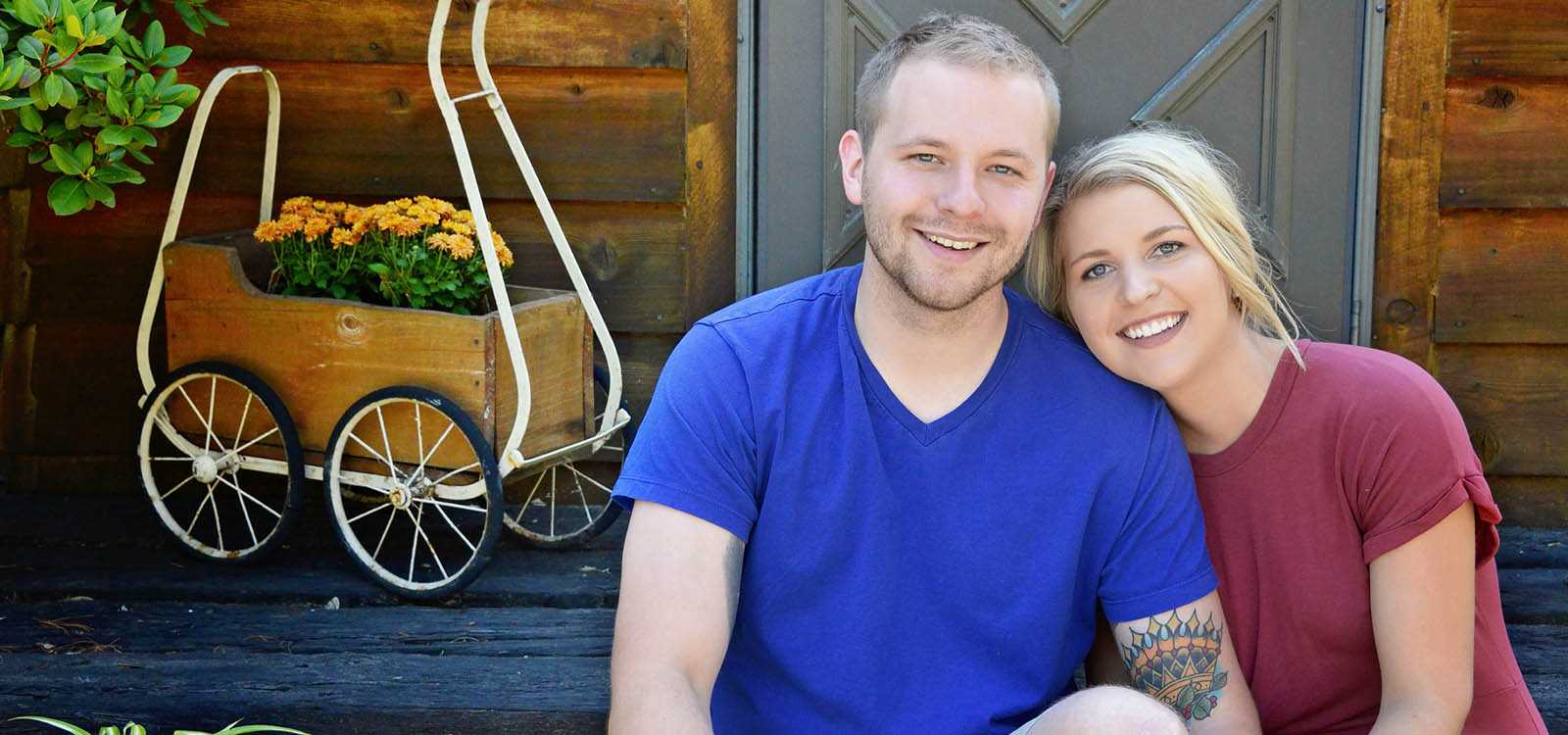 smiling couple sitting on front porch of home