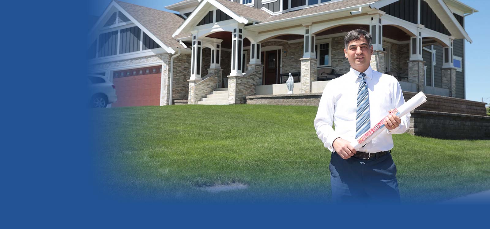 Man holding blueprint in front a new home