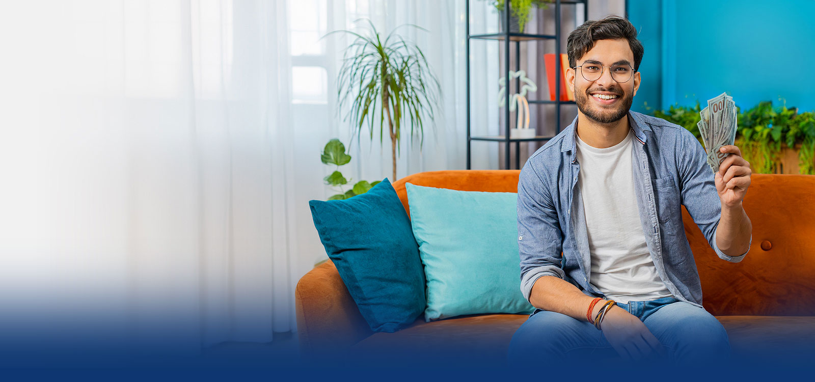 Young man on his couch holding money